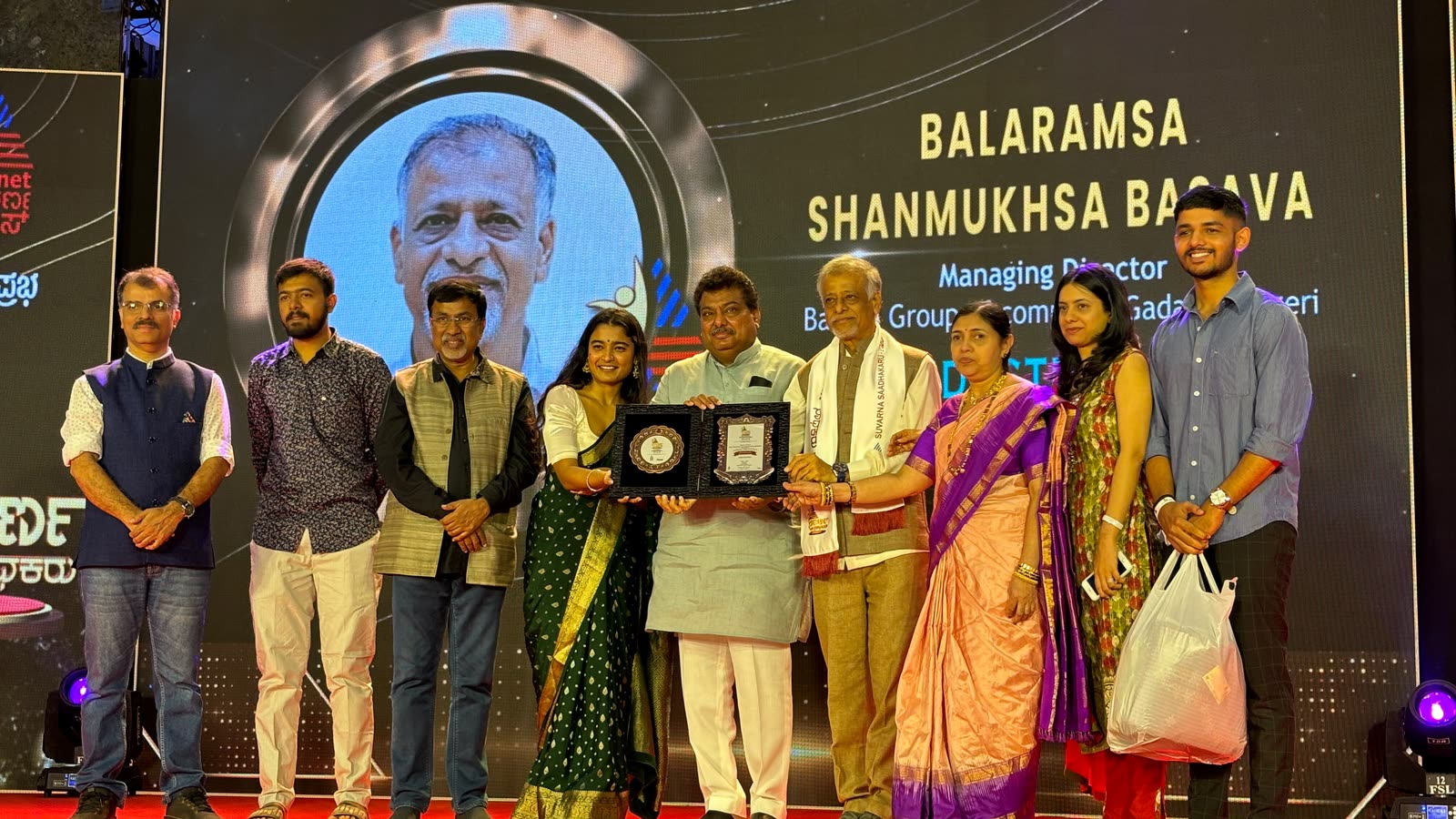 Balramsa Basava receiving the Suvarna Saadhakaru 2024 award on stage, with the family
